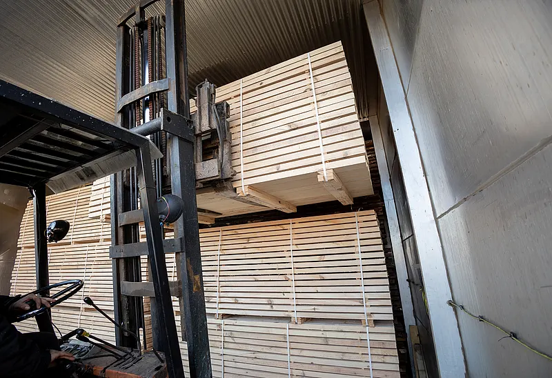 Forklift placing stacked timber packages into a kiln drying chamber