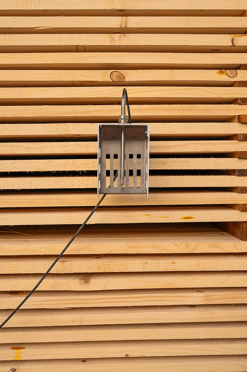 HTP501 humidity and temperature probe mounted in front of stacked wooden boards for monitoring.